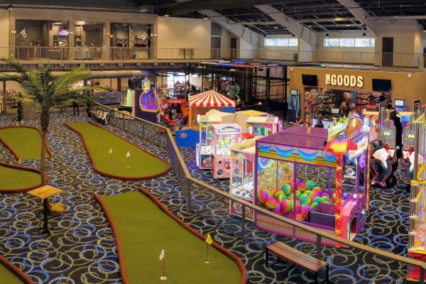 The image shows an indoor entertainment center with mini-golf, arcade games, and a shop called 