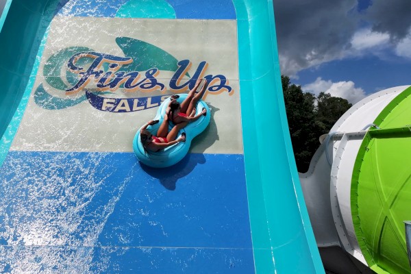 Two people are riding a blue raft down a water slide labeled 