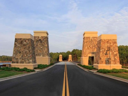 The image shows a road crossing a bridge with four stone towers, likely part of the bridge's design and architecture, under a partly cloudy sky.