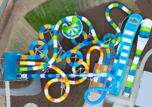 An aerial view of a colorful water park with multiple winding slides, including tubes and open slides, and green and blue elements, seen from above.