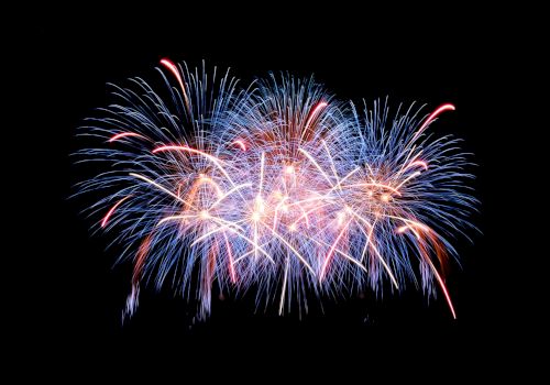 The image shows a colorful burst of fireworks in the night sky, with blue, red, and white streaks radiating outward in a celebratory display.