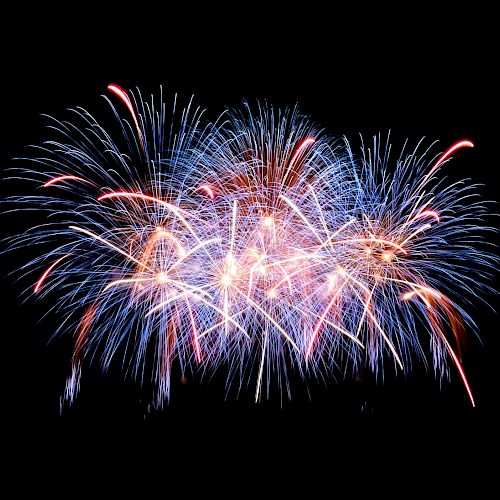 The image shows a colorful burst of fireworks in the night sky, with blue, red, and white streaks radiating outward in a celebratory display.