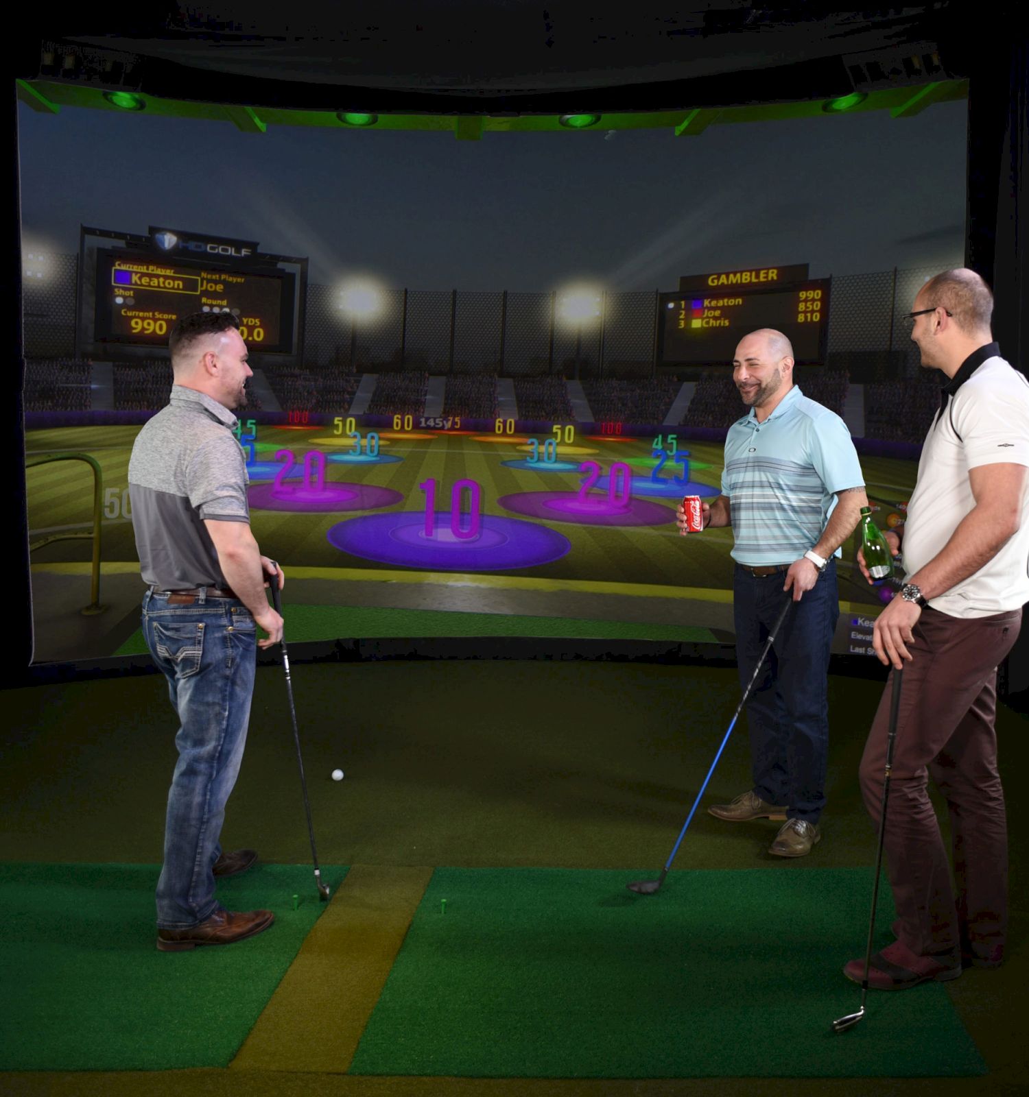 Three people are playing simulated golf in an indoor environment, standing on a green mat with golf clubs, facing an animated target screen.