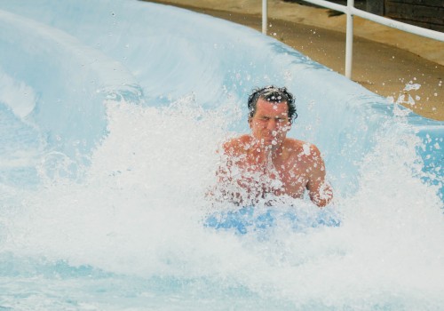 A person is riding a water slide, splashing into the pool below, creating a large splash and appearing to have fun.