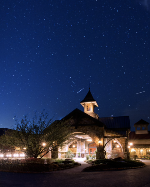 A well-lit building with a clock tower is set against a clear, starry night sky, creating a scenic and serene atmosphere.