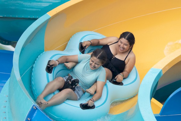 Two people are enjoying a water slide, riding together in a blue inflatable tube. They appear to be having an exciting time on the slide.