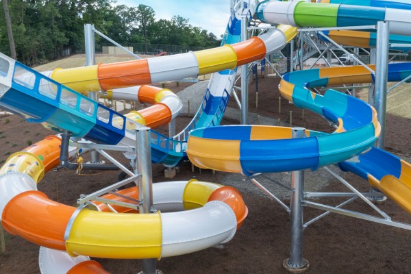 The image shows a colorful water slide complex featuring multiple twisting and turning slides in blue, yellow, orange, and white.