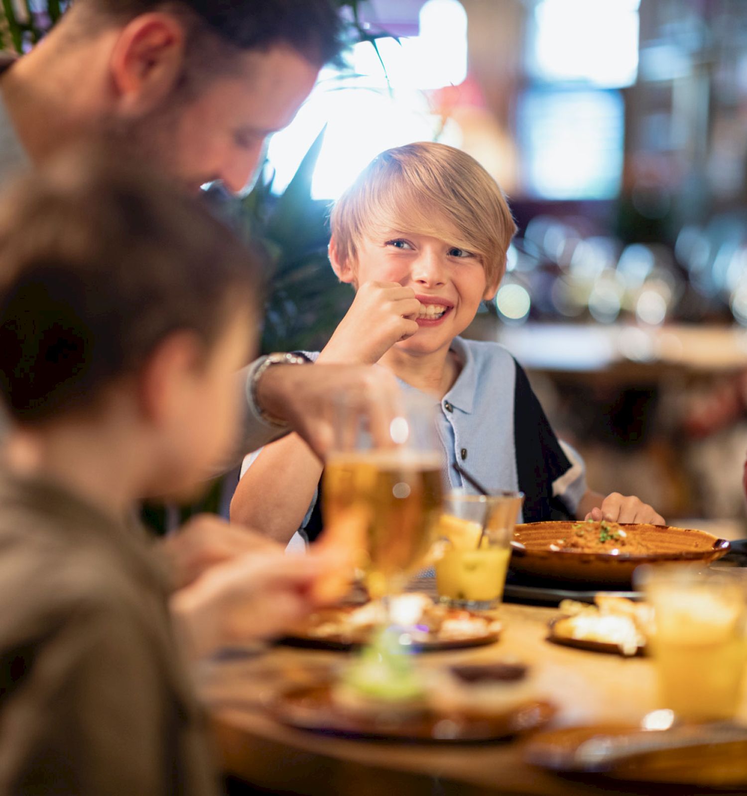 A family of four is enjoying a meal at a restaurant, with various dishes and drinks on the table.