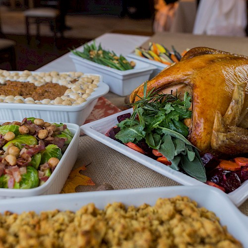 A table with a roasted turkey, stuffing, green beans, salad, and other dishes, likely for a festive meal, is shown in the image.